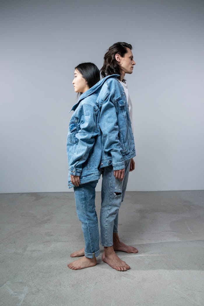 Two individuals in denim outfits standing back-to-back, highlighting casual urban fashion.